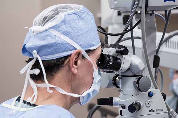 Doctor looking through medical equipment while performing a medical procedure on the patient’s eye.