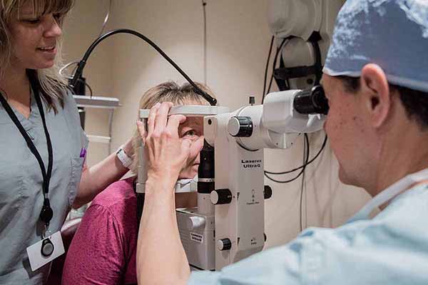 Doctor performing an eye exam on a patient as a nurse assists the doctor.