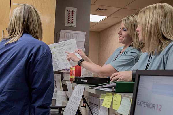 Three eye technicians gathering and looking at a patient’s medical chart.