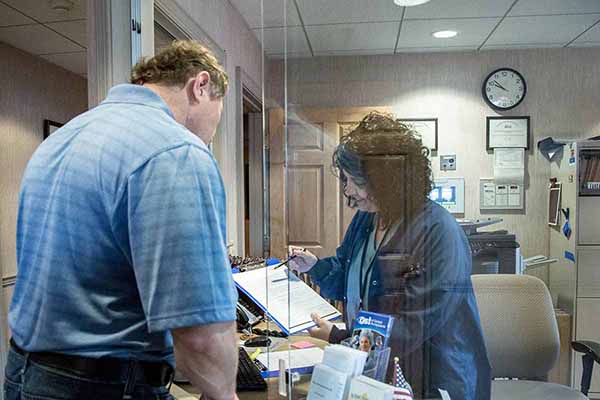 A patient checks in with the receptionist at the office.